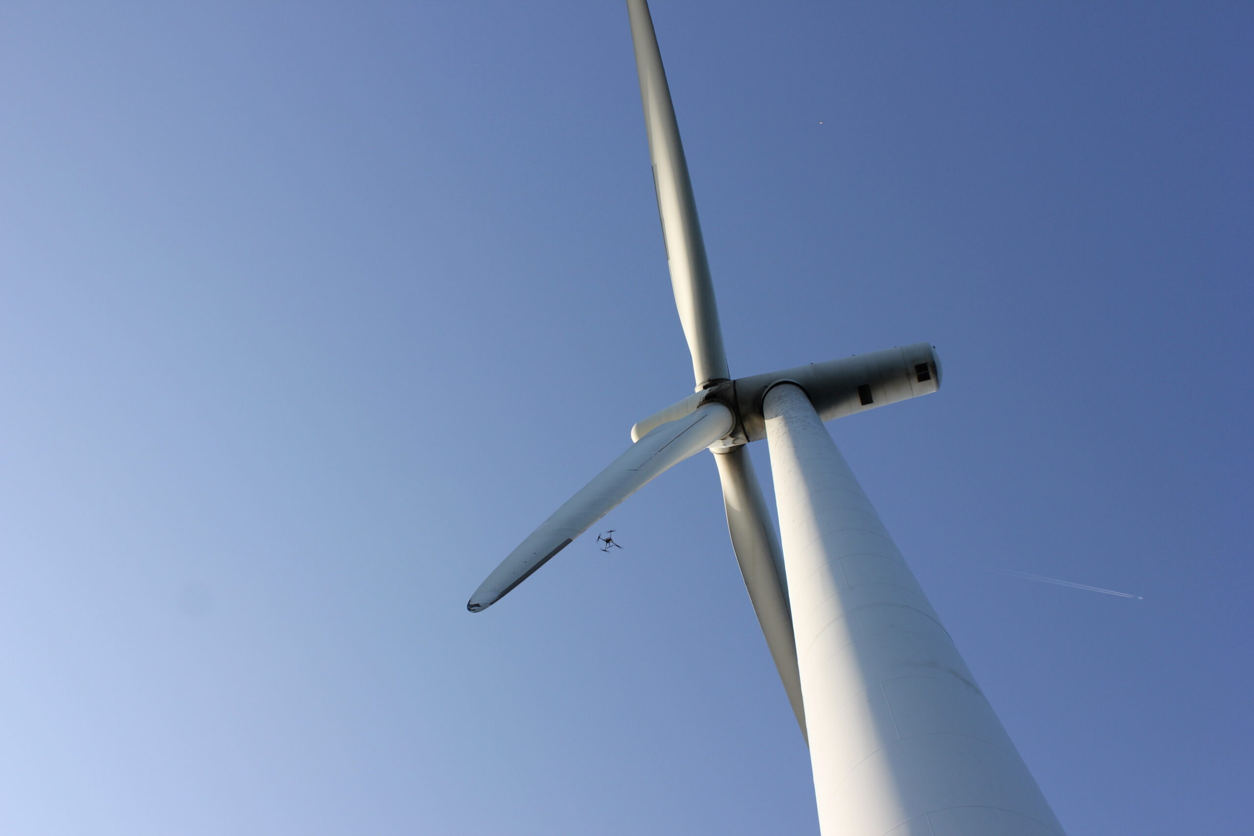 Drone-based inspection crew working in the field near a wind turbine